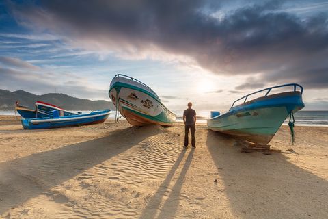 A person standing between fishing boeats at Puerto Lopez beach