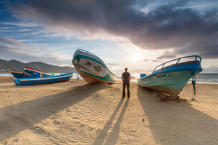 A person standing between fishing boeats at Puerto Lopez beach
