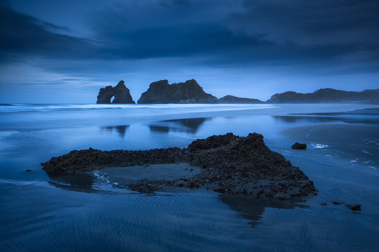 The sea stacks at Wharariki beach under a dark blue twilight sky