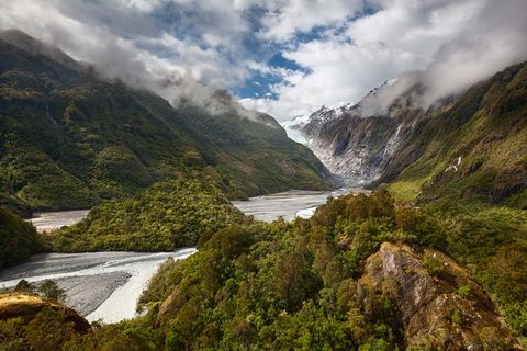 Franz Josef Glacier with the rainforest in the foreground on a sunny day