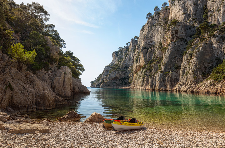 Stony shore with two Kayaks in front of high cliffs
