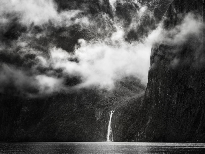 Clouds above a waterfall and immense cliffs