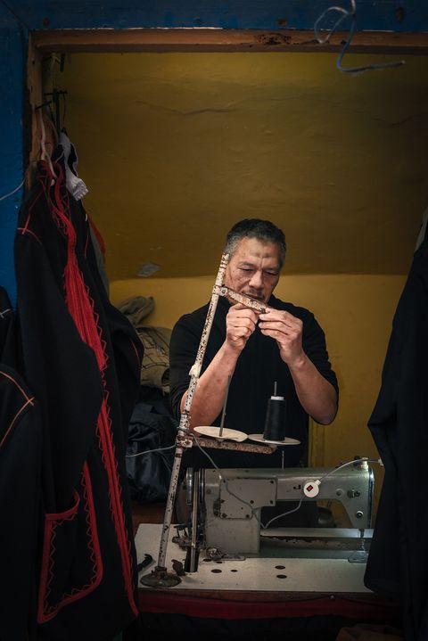 Moroccan tailor working with a sewing machine in a small, yellow-walled workshop in Essaouira.