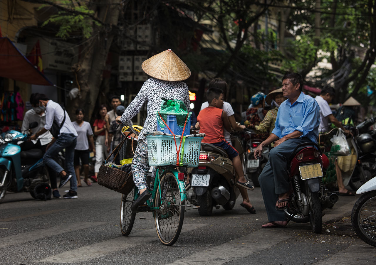 Asiatische Person auf einem Fahrrad auf den Straßen von Hanoi