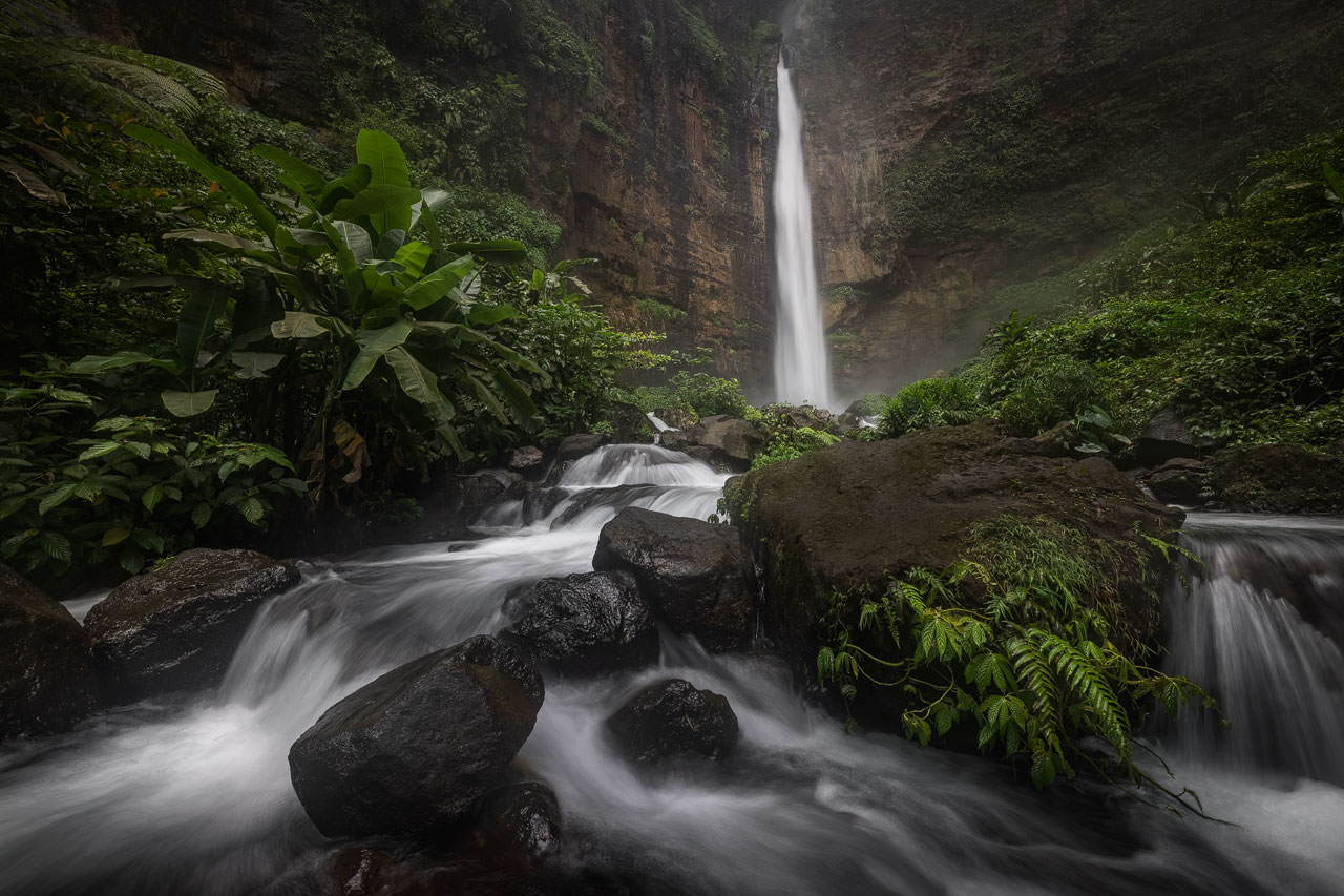 Ein Fluß führt durch eine üppige Landschaft zum Kapas Biru Wasserfall