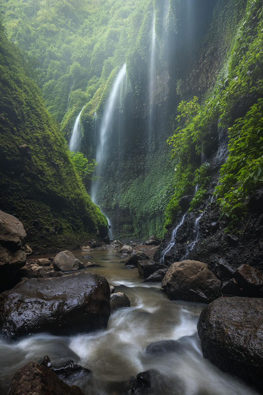 The green cliffs and cascades of the Madakaripura waterfall near Mount Bromo