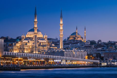 Istanbul skyline at dusk with illuminated mosques, minarets, and waterfront restaurants by the Bosphorus.