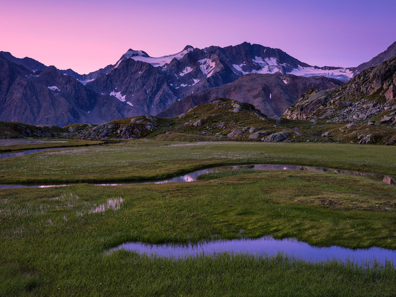Colorful dawn in the Stubai Mountains with alpine meadows and glaciers.
