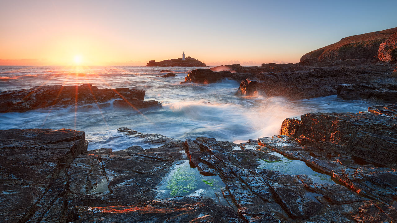 The sun sets behind Godrevy Lighthouse.