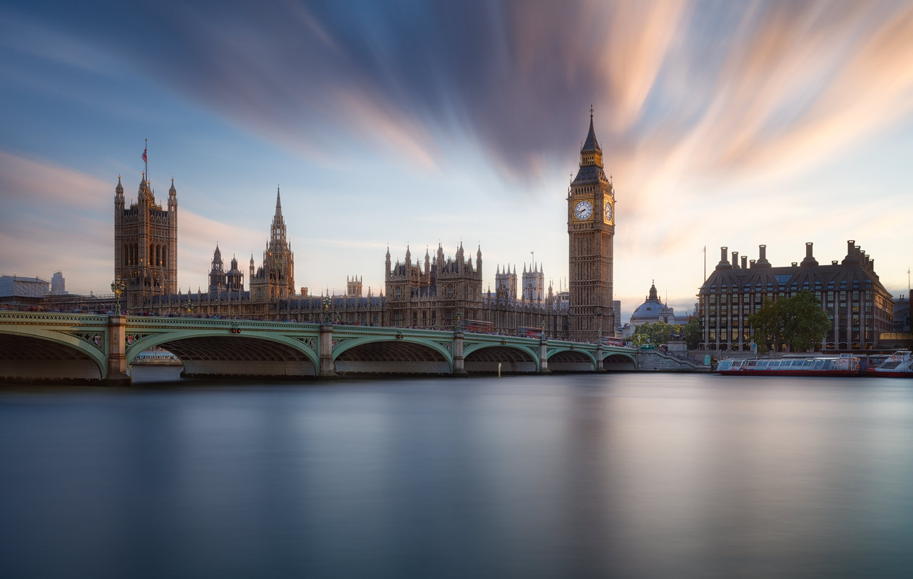 Clouds drifting over the Houses of Parliament which are bathed in golden light