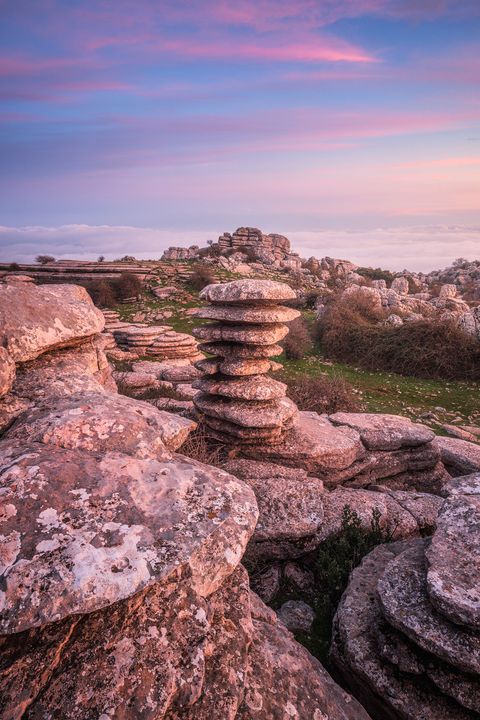 Limestone rock formations in El Torcal de Antequera, Spain, under a pink and purple sunset sky.