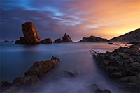 The jagged coastline at Playa de la Arnia with Santander glowing in the distance