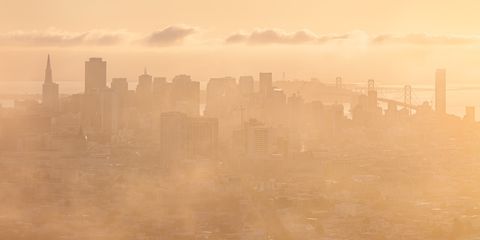 San Francisco skyline and Bay Bridge enveloped in golden sunrise fog.