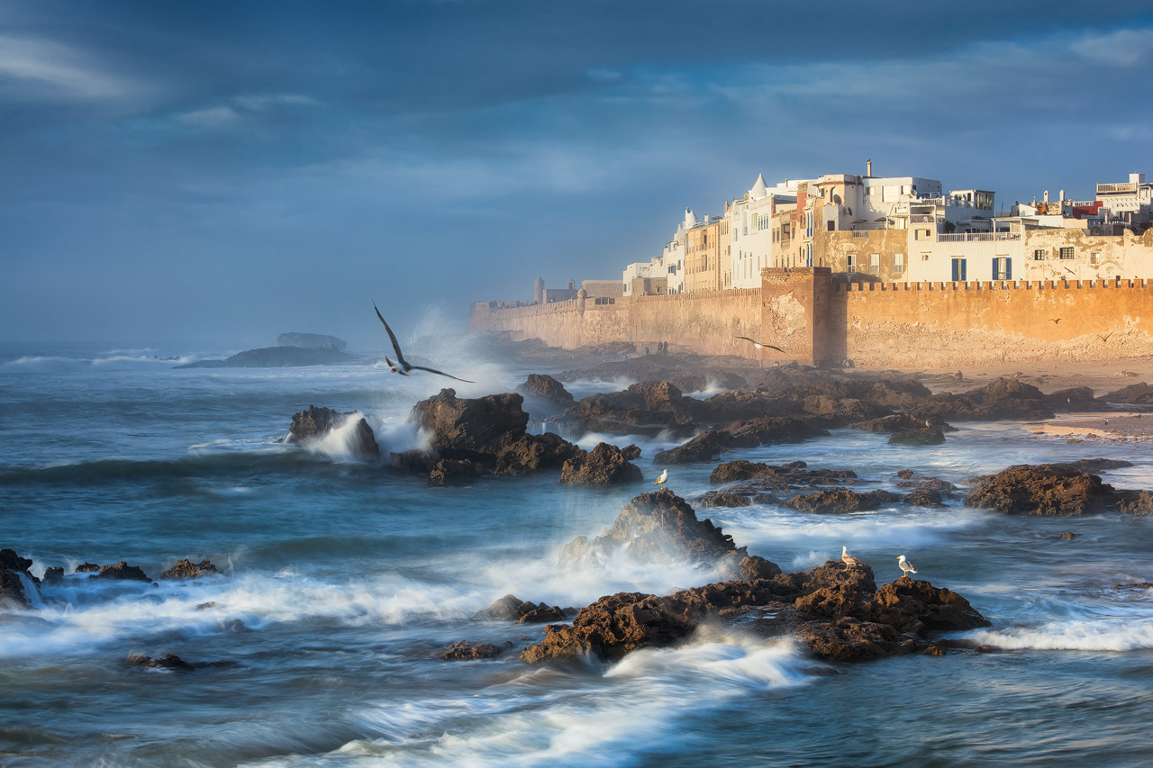 Waves crash along the coast of Essaouira during sunset.